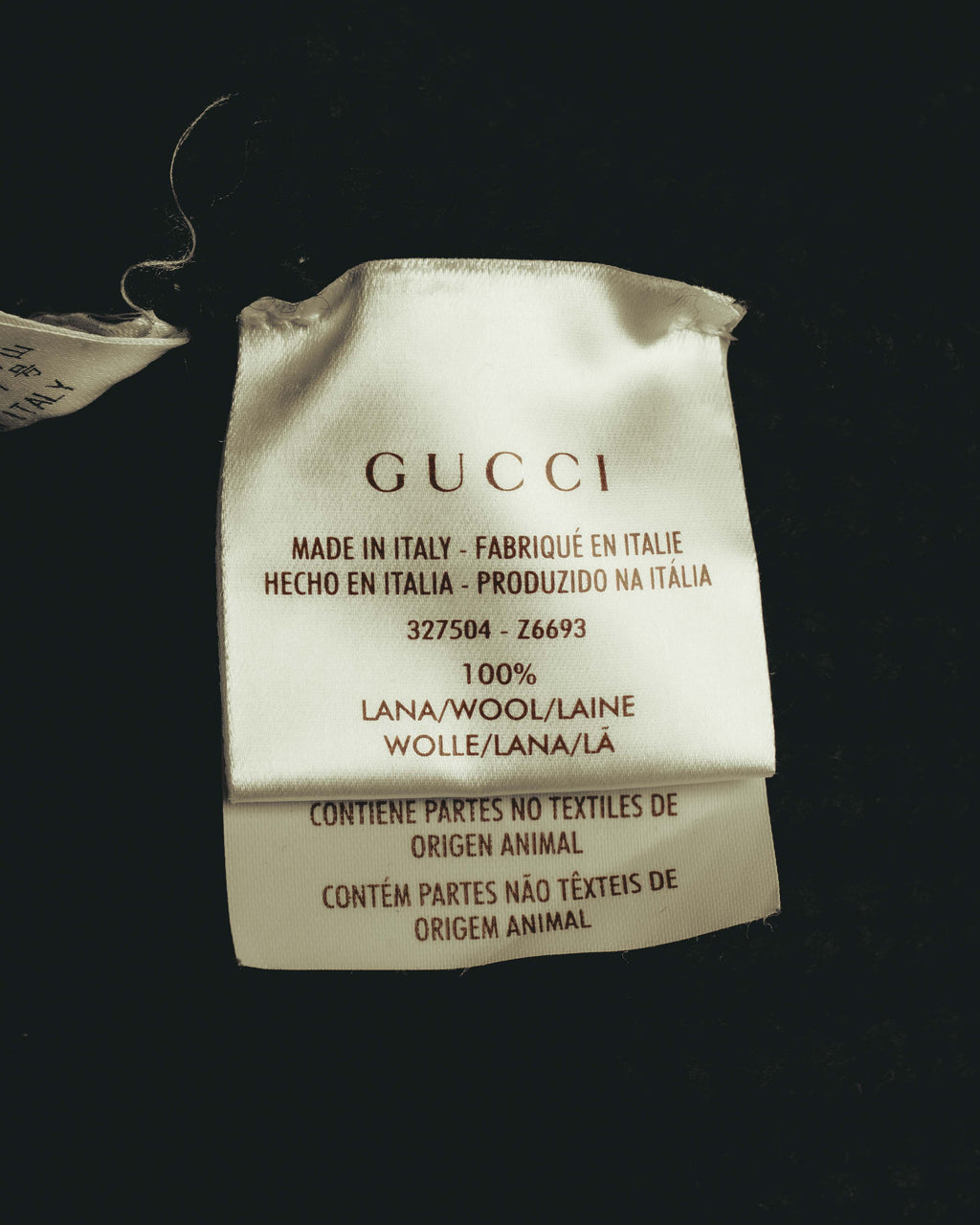 GUCCIロゴ、イタリア製表記、品番「327504 - Z6693」とウール100％の素材表記が確認できる内タグのカット。