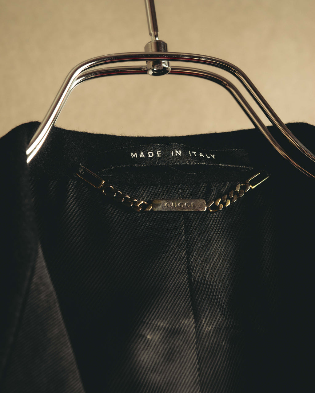 内側の襟元に配された「MADE IN ITALY」表記と、GUCCI刻印入りチェーン式ハンガーループを捉えたディテールカット。総裏仕立ての滑らかな裏地も確認できます。