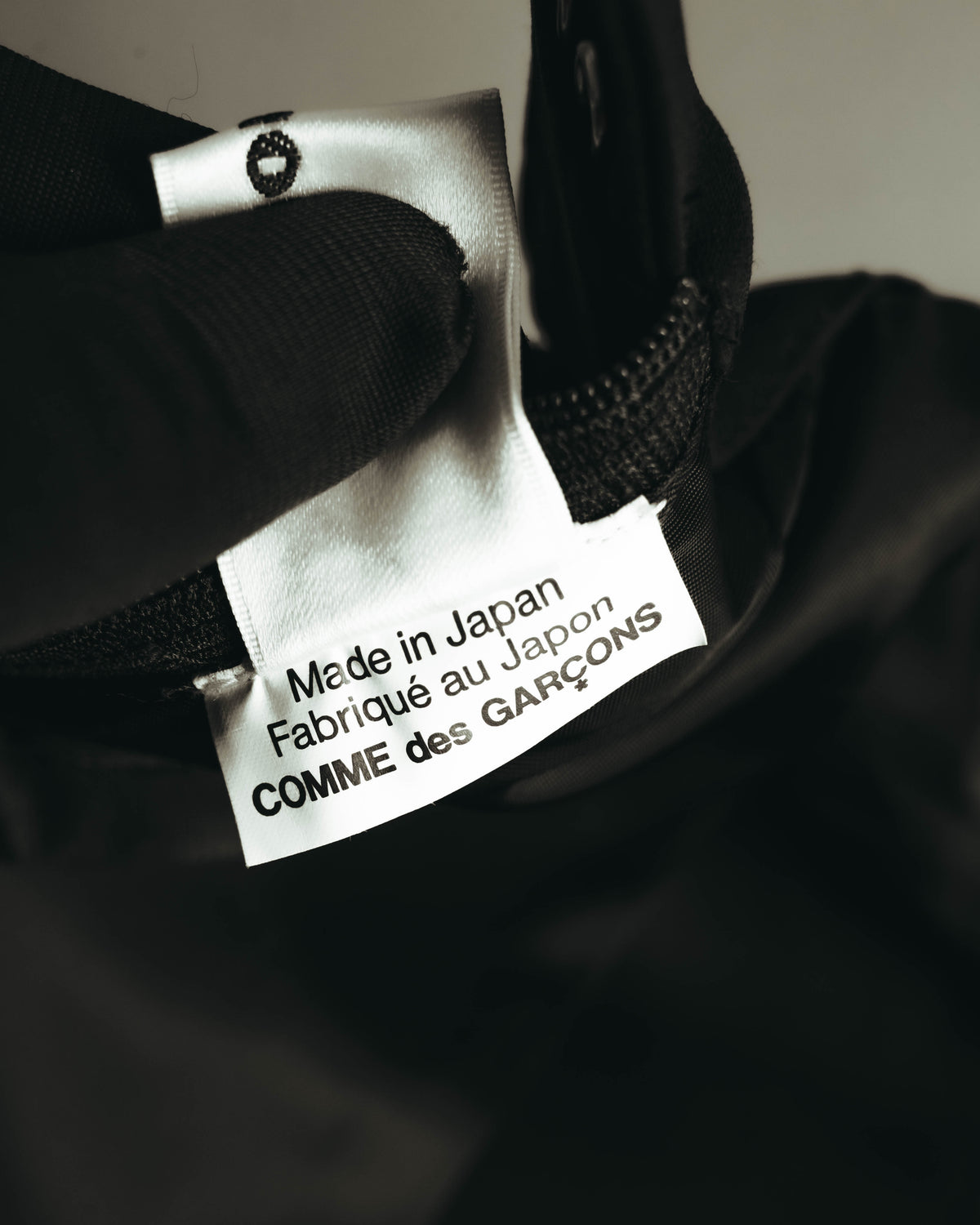 内側に配されたブランドタグのクローズアップ。"Made in Japan / Fabriqué au Japon / COMME des GARÇONS"の表記が確認できます。