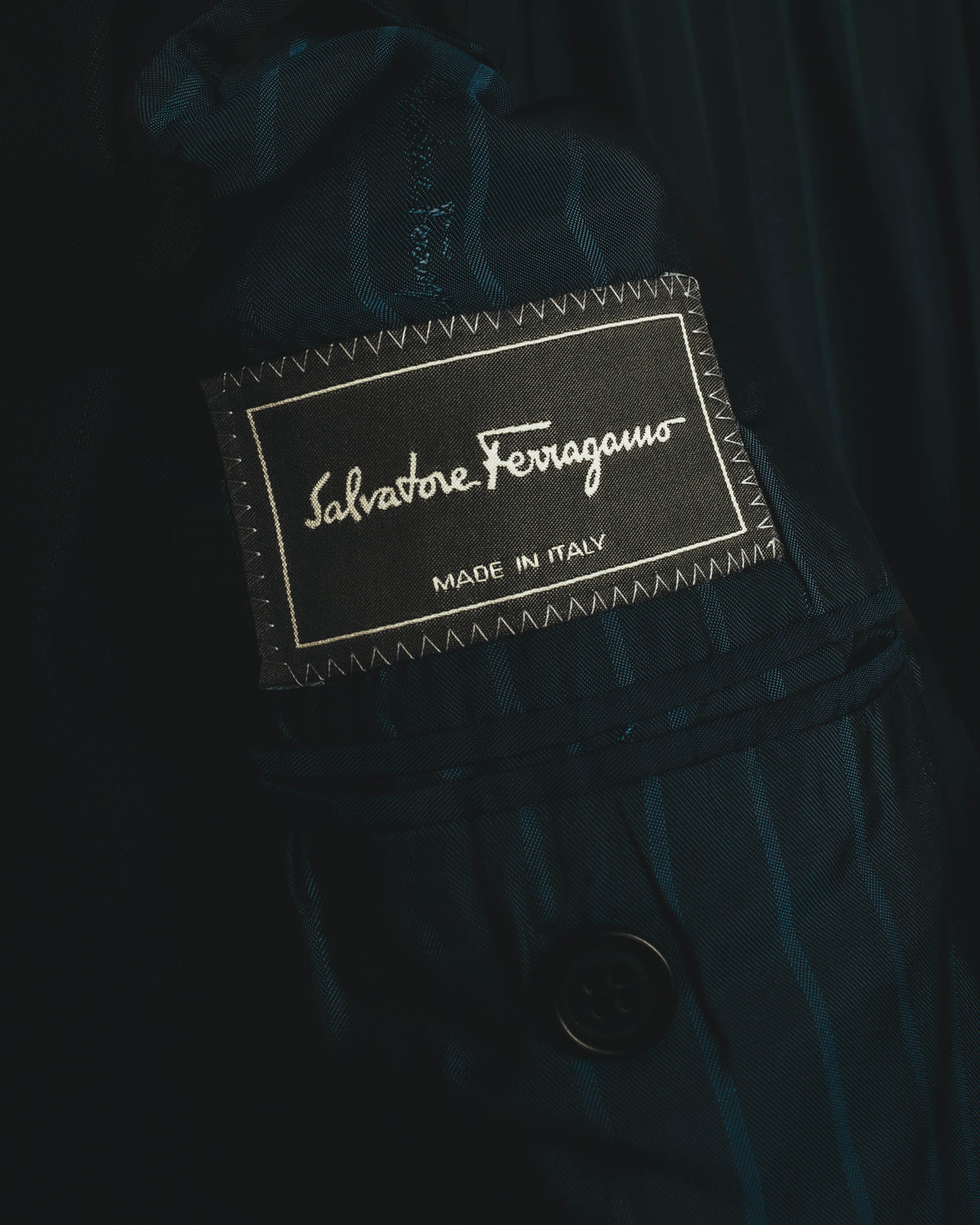 内側に配されたSalvatore Ferragamoのブランドネームタグ。MADE IN ITALY表記と、青緑を帯びたダークトーンのストライプ裏地を確認できるカット。