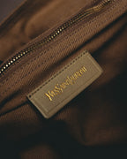 ブラウン系の綾織テキスタイルの内装に配された、旧 Yves Saint Laurent ワードマーク入りのレザーパッチとゴールドカラーの金属ファスナー。