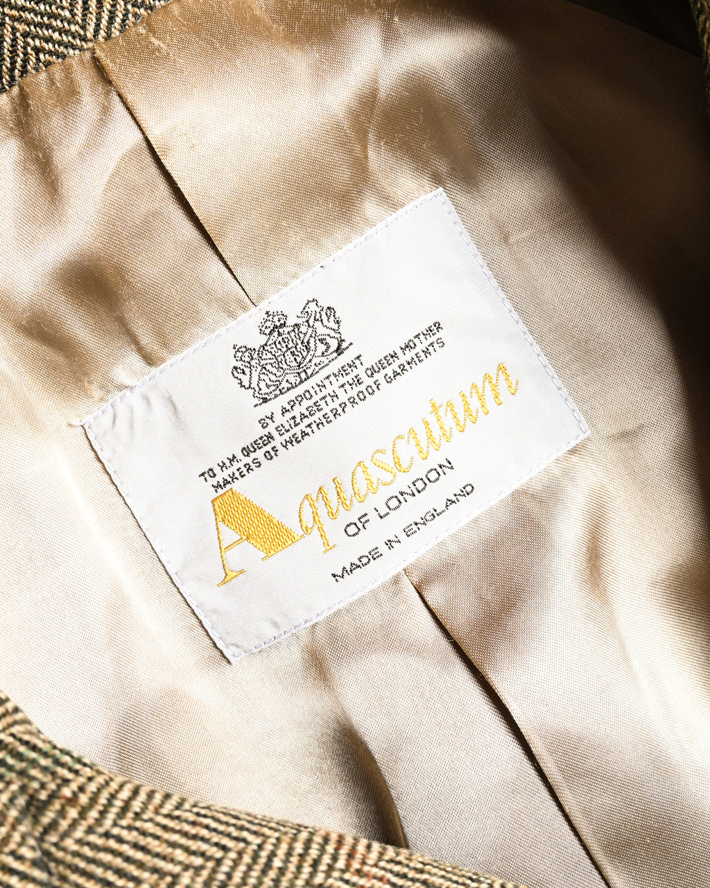 滑らかな総裏仕立ての内側に配されたブランドタグ。王室御用達を示す表記、Aquascutum OF LONDON、MADE IN ENGLANDの文字を確認できる旧仕様のタグです。