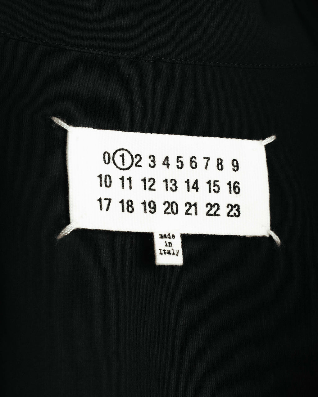 ネック内側に配されたカレンダータグのアップ。数字「1」が選択され、下部のピスタグには「made in Italy」表記が確認できます。