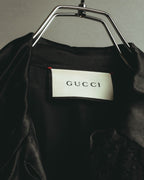 首元に配されたGUCCIロゴ入りのブランドタグを写したカット。ブラックの生地に白地の織りタグと赤い縫い留めが確認できます。