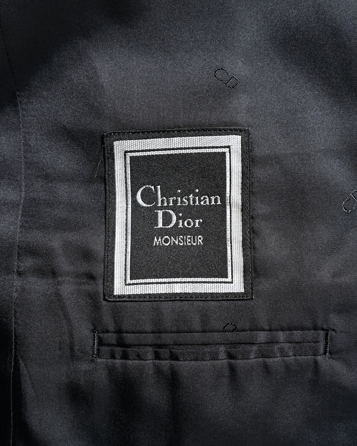 総裏仕立ての内側に配された「Christian Dior Monsieur」の織りラベルを捉えたカット。裏地には同色のCDモノグラムが反復されています。