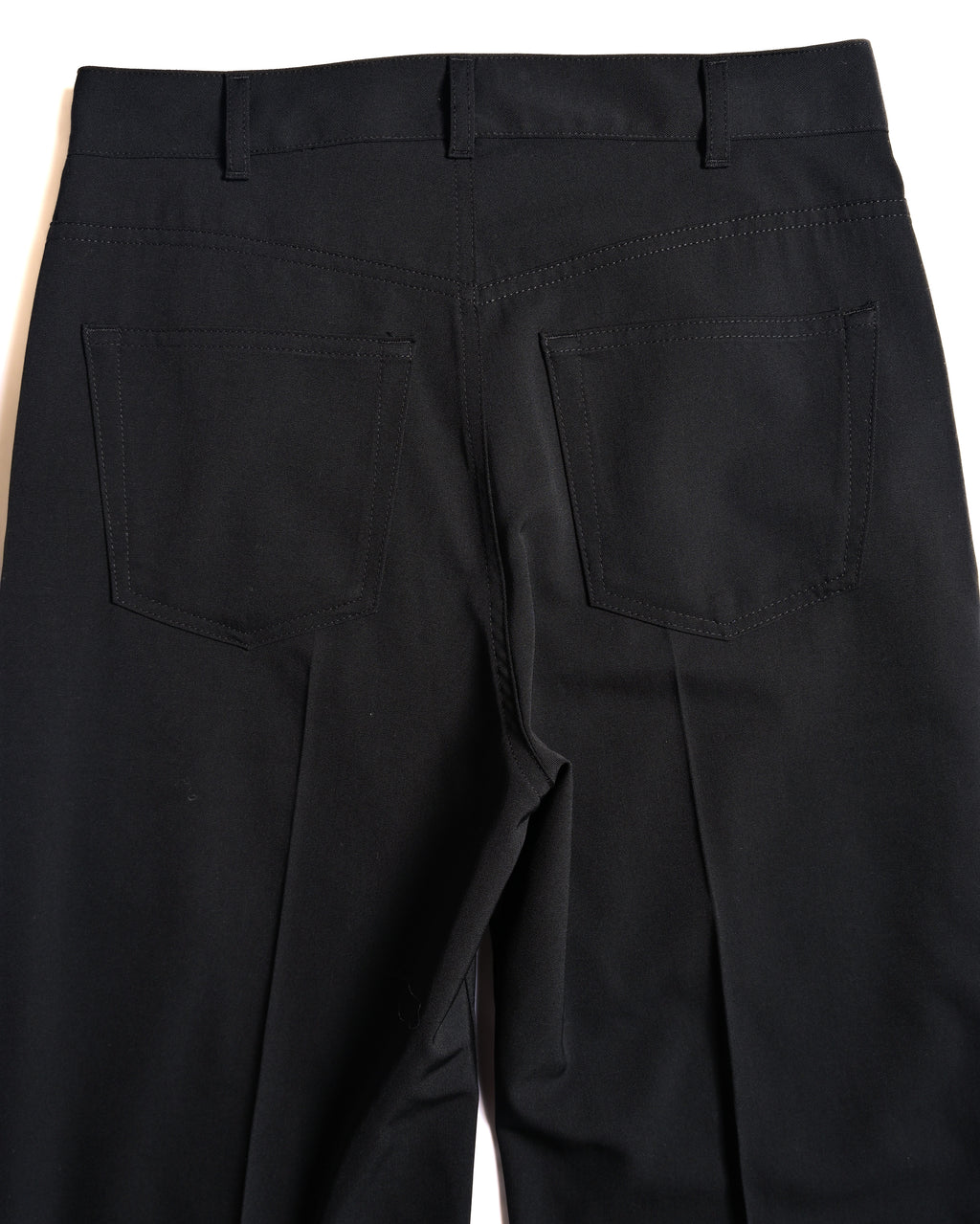 背面の腰回りを捉えたカット。デニムパンツを踏襲した5ポケット仕様のバックポケットと、縦のラインを強調するバックのセンタークリースを確認できます。