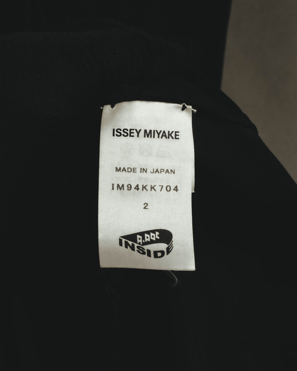 ISSEY MIYAKEおよびA-POC INSIDEの表記、品番「IM94KK704」、日本製表記とサイズ2を確認できる内タグ。