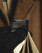 「NEW WOOL 100%」およびカシミヤ50%の表記が確認できる、表地の素材表示タグ。ブラウンの起毛感を備えたウール系繊維の素材構成を示すカット。