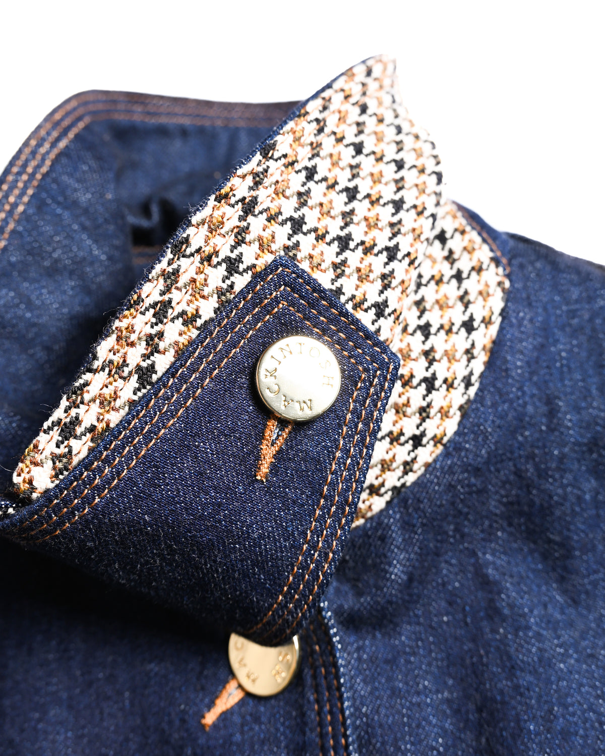 アイボリー、ブラック、ブラウンを基調とした襟裏の千鳥格子調チェックと、ストラップに配されたゴールドカラーのブランド刻印入りボタンを捉えたディテールカット。襟元はストラップを留めることでスタンドカラーとしても着用できます。