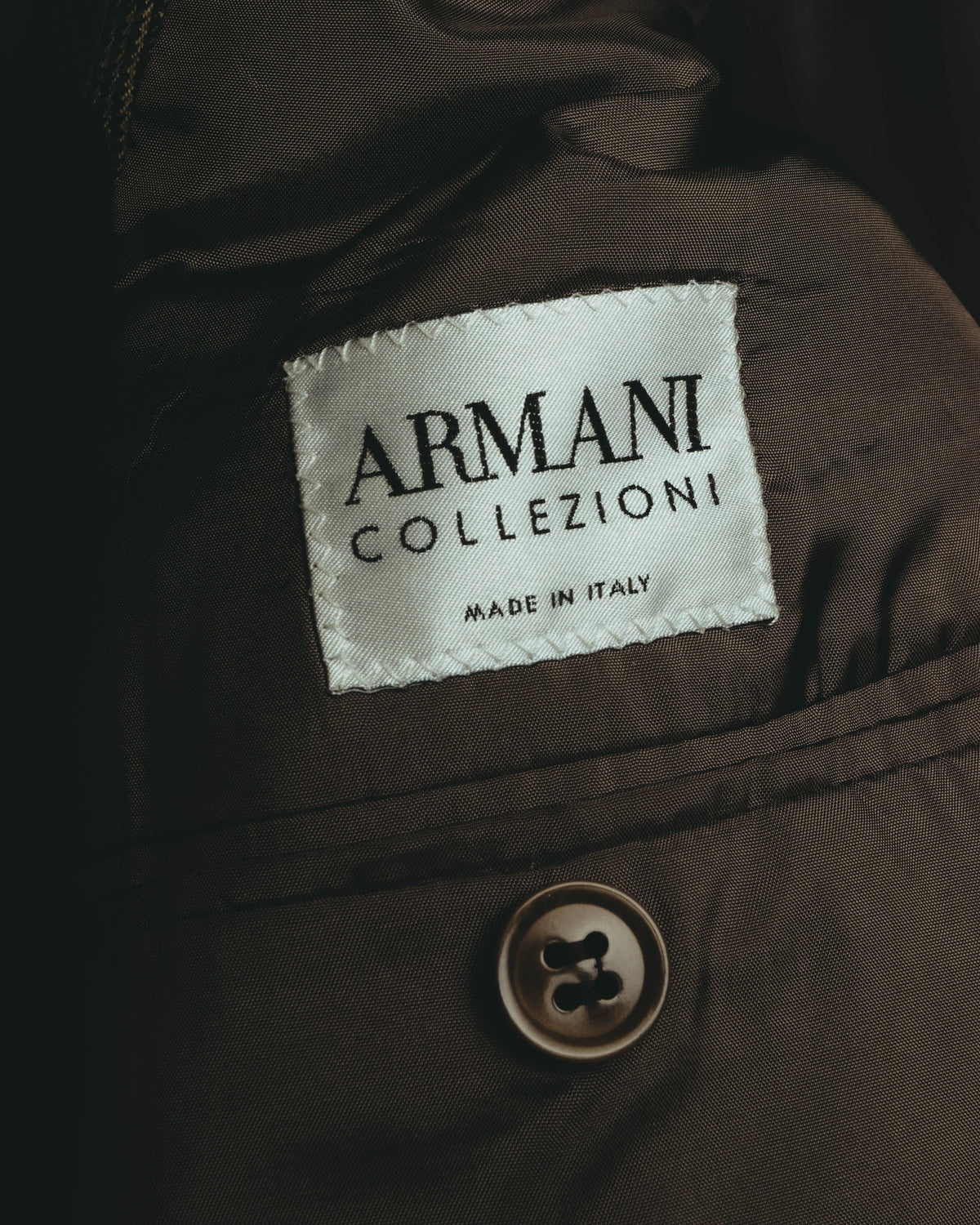 ジャケット内側のARMANI COLLEZIONIタグと、MADE IN ITALY表記を捉えたカット。落ち着いたブラウンの裏地と、全体の色彩に馴染む同系色ボタンも確認できます。
