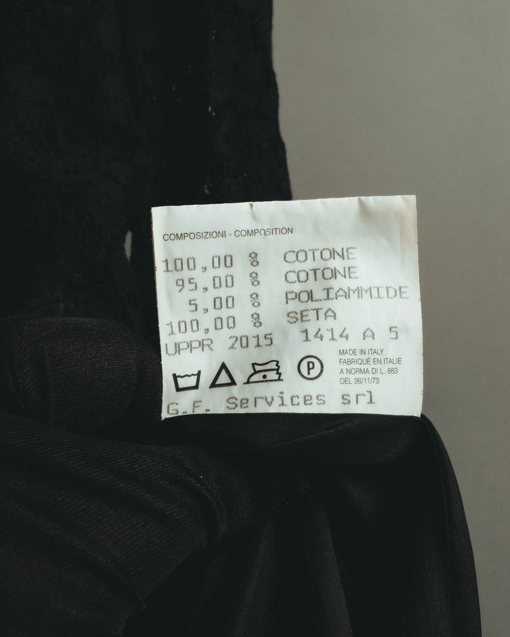コットン、ポリアミド、シルクの混率とケア表示を確認できる品質表示タグ。2015年表記およびイタリア製の記載が読み取れるカット。