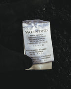 襟元に付くVALENTINO MADE IN ITALYのネームタグと、TACTELナイロンを含むポリアミド、ヴァージンウールの素材表示。ブラックのループ状の凹凸を持つニット地も確認できるカット。
