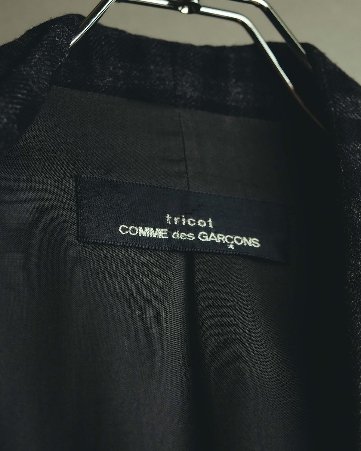 首元内側に配された旧型のtricot COMME des GARÇONSネームタグを捉えたカット。肩周りを中心に取り入れられたキュプラ裏地の仕様も確認できます。
