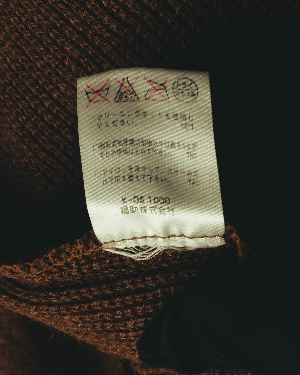 ニット内側に縫い付けられた品質表示タグのカット。クリーニング表示と福助株式会社の表記が確認できます。