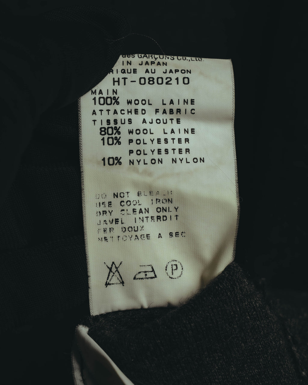 本体は毛100%、裾の別布は毛80%・ポリエステル10%・ナイロン10%の混紡と記載された品質表示タグ。MADE IN JAPANおよび品番HT-080210の表記も確認できる。