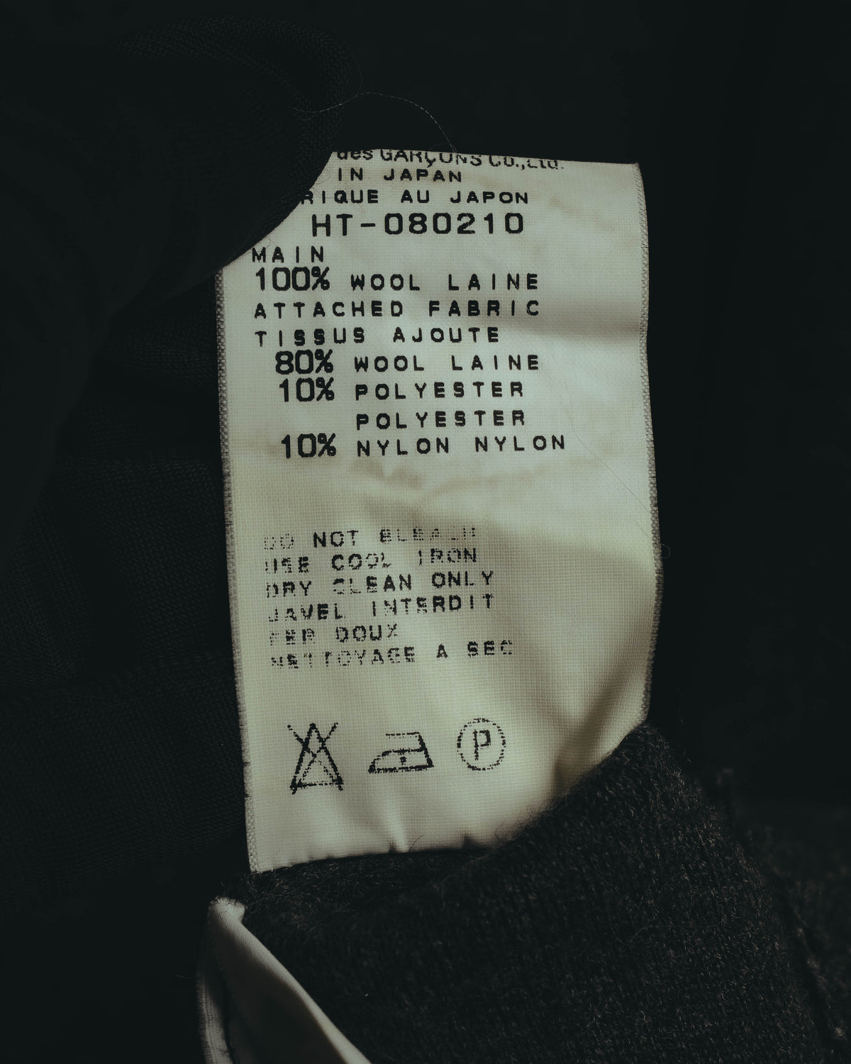 本体は毛100%、裾の別布は毛80%・ポリエステル10%・ナイロン10%の混紡と記載された品質表示タグ。MADE IN JAPANおよび品番HT-080210の表記も確認できる。