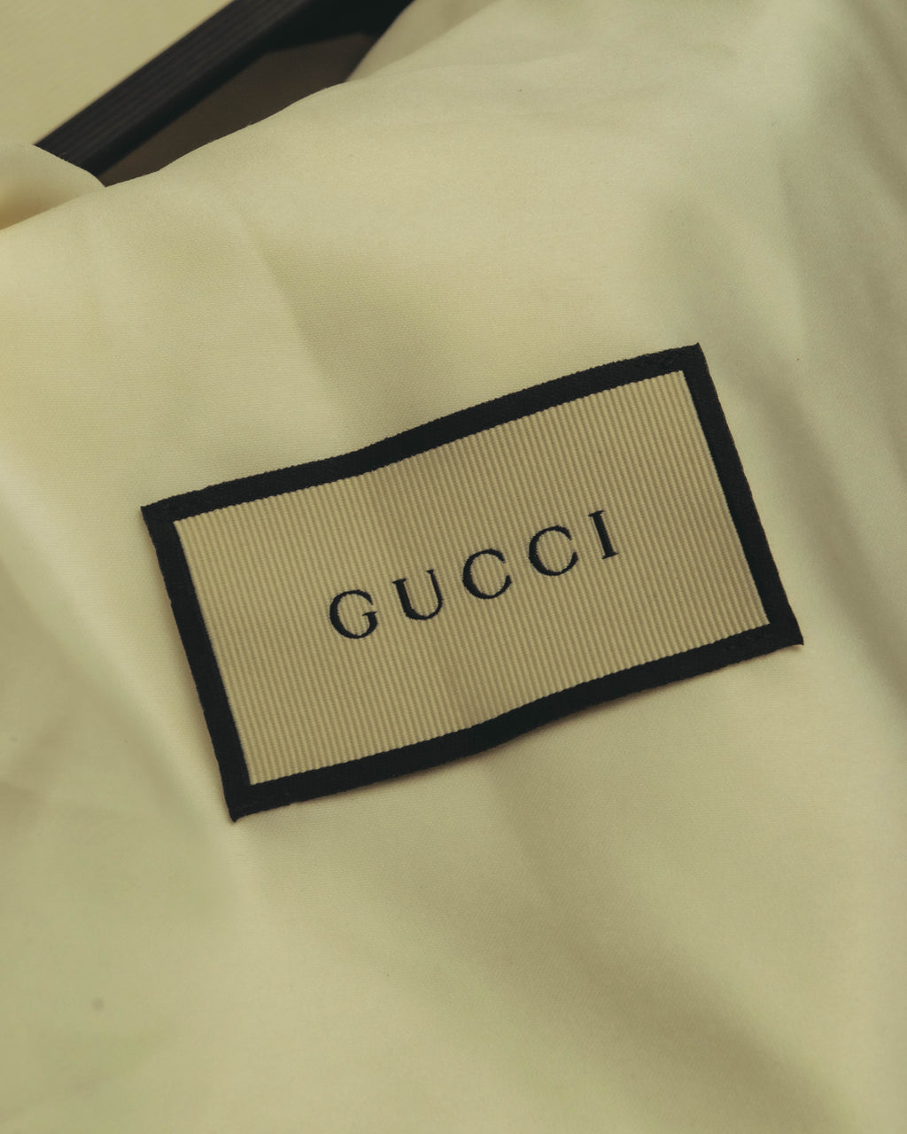 参考付属品として揃う、GUCCIロゴ入りダストバッグのタグ部分。生成りの布地に黒縁の織りネームが配されています。