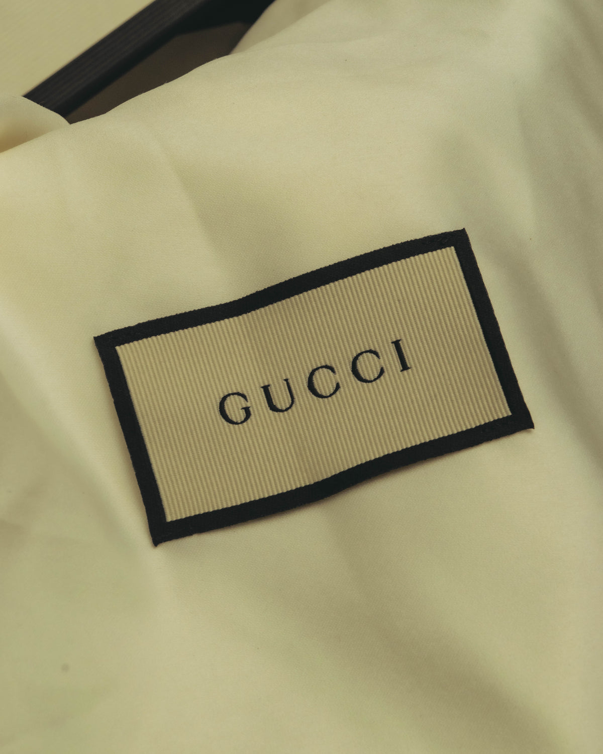 参考付属品として揃う、GUCCIロゴ入りダストバッグのタグ部分。生成りの布地に黒縁の織りネームが配されています。