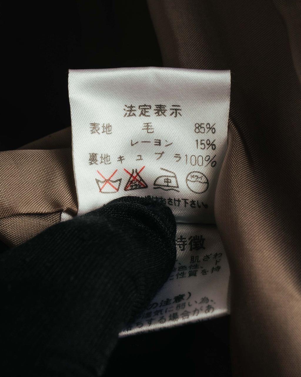 内側の品質表示タグを写したカット。表地は毛85%・レーヨン15%、裏地はキュプラ100%と記載されています。