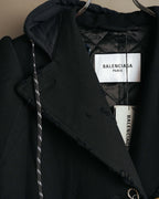 襟元に配された白地に黒文字の「BALENCIAGA PARIS」タグと、内側のキルティング仕立ての裏地を捉えたカット。チャコールブラック調のフードとフロント端の裁ち切り処理も確認できます。