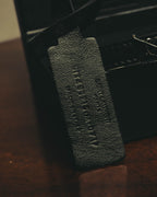 SAINT LAURENT PARISの刻印が施されたブラックレザーストラップと、端部の留め具（クラスプ）を捉えたディテールカット。レザーのシボ感とブラックで統一された仕上がりが確認できます。