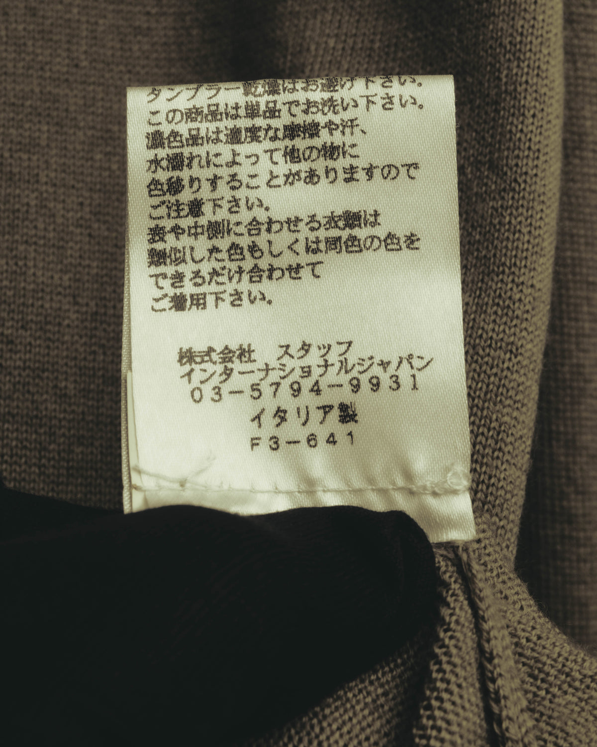 襟元内側の品質表示タグを写したカット。株式会社スタッフ インターナショナルジャパンの表記とイタリア製表記を確認できます。