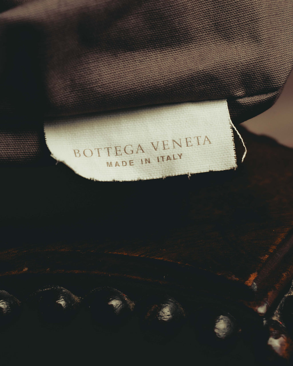 ブラウン系の内装生地に配された、BOTTEGA VENETAとMADE IN ITALYの二段表記による生成り色の織物タグ。
