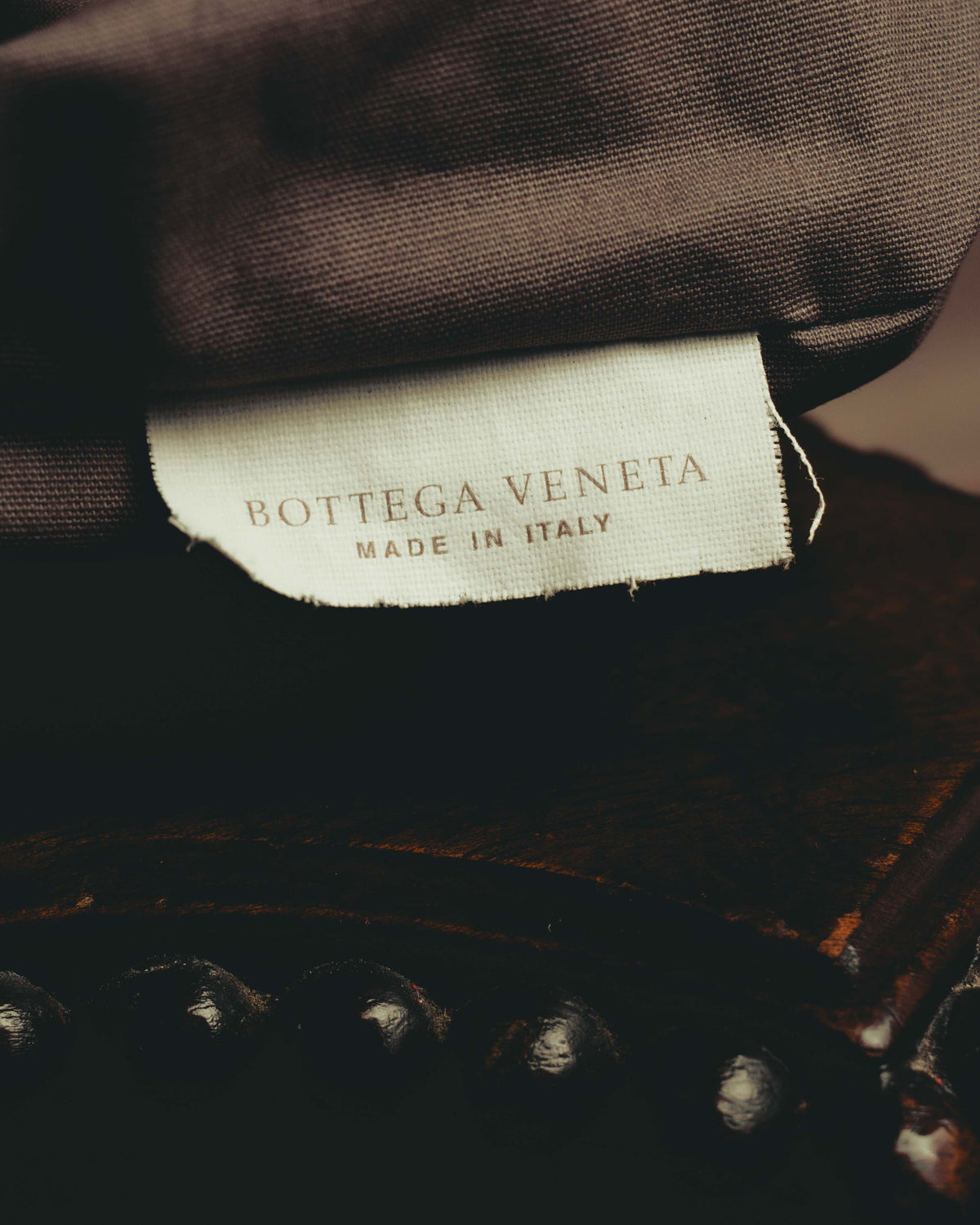 ブラウン系の内装生地に配された、BOTTEGA VENETAとMADE IN ITALYの二段表記による生成り色の織物タグ。