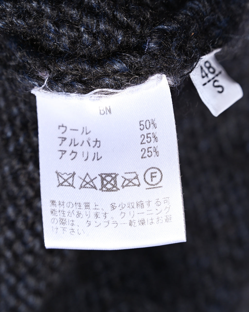 ウール50％・アルパカ25％・アクリル25％の混率とケア表示を確認できる内側の素材・洗濯表示タグ。サイズ表記は48／S。