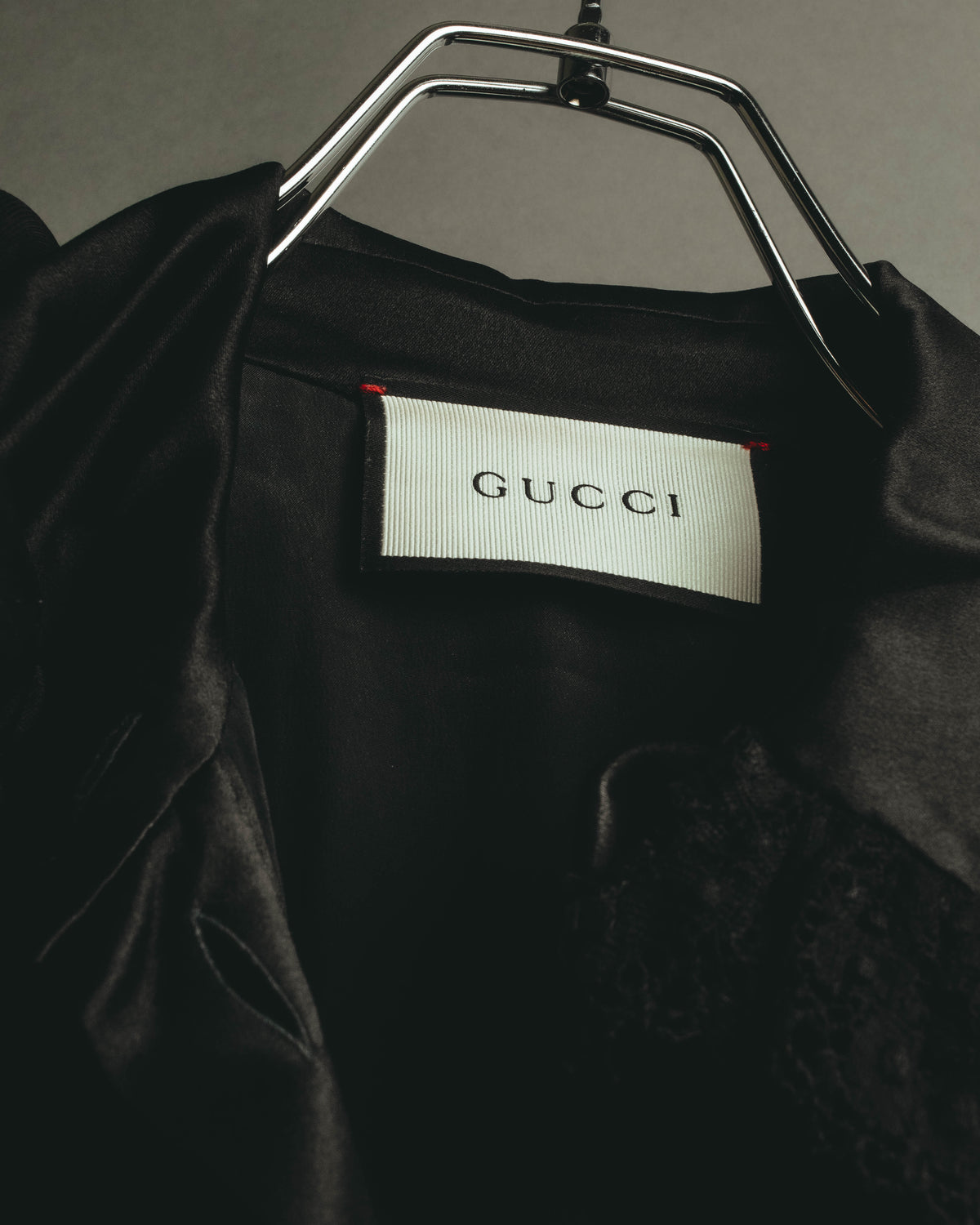 首元内側に配されたGUCCIロゴ入りのブランドタグ。ブラックの光沢生地とのコントラストが確認できるカット。