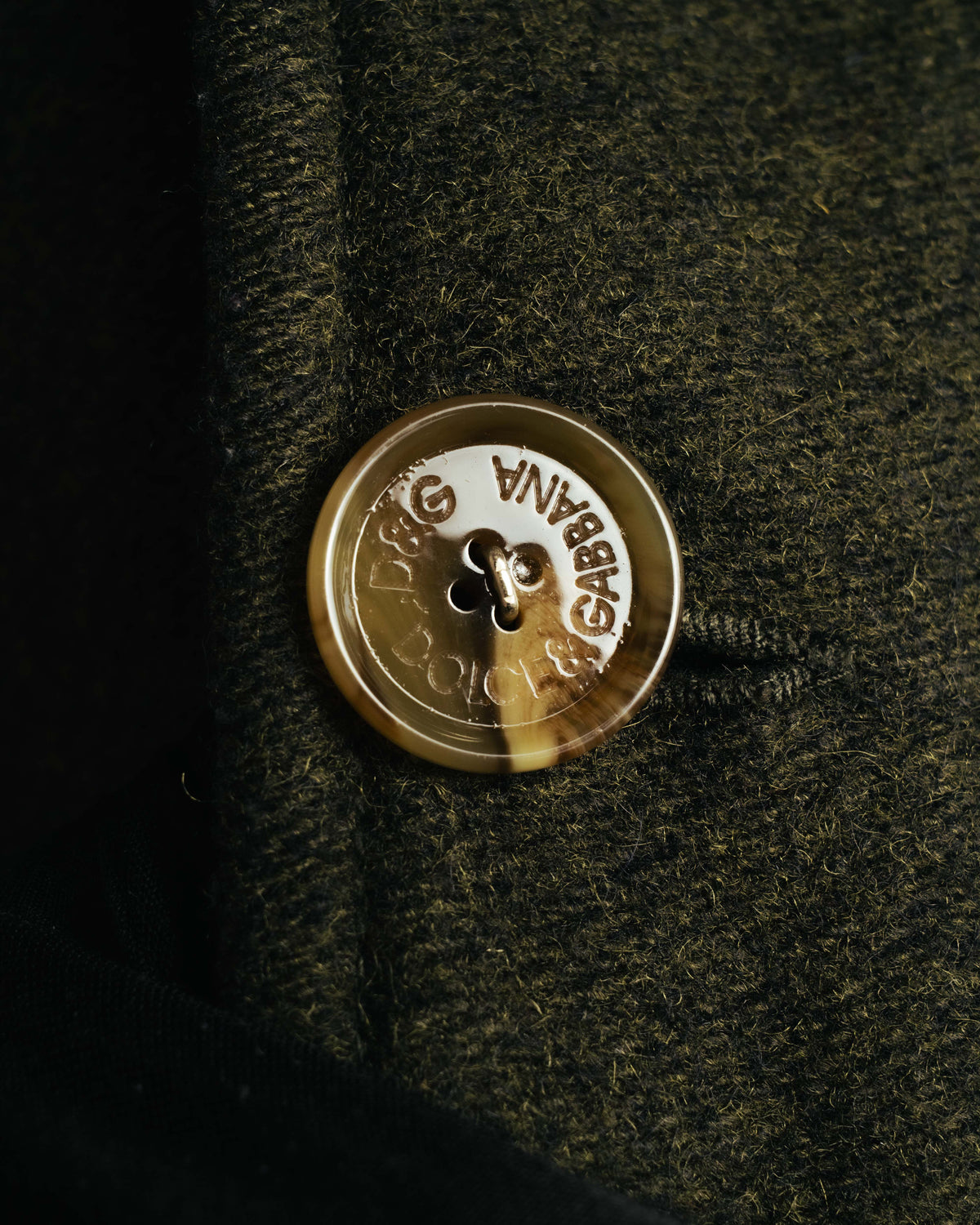 ダブルブレストのフロントに配された、D&G DOLCE & GABBANAの刻印入りボタンのアップ。厚みあるウール混生地の繊細な起毛感も確認できるディテールカット。