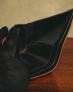 開いた小銭入れ内部を捉えたディテールカット。ブラックの布地状ライニングと、縁に施されたブラウン系のコバが確認できます。