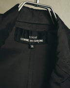 首元の内タグに「tricot COMME des GARÇONS」表記とサイズ「M」を確認できるカット。深いチャコールの滑らかな裏地と中央の縫製も写しています。