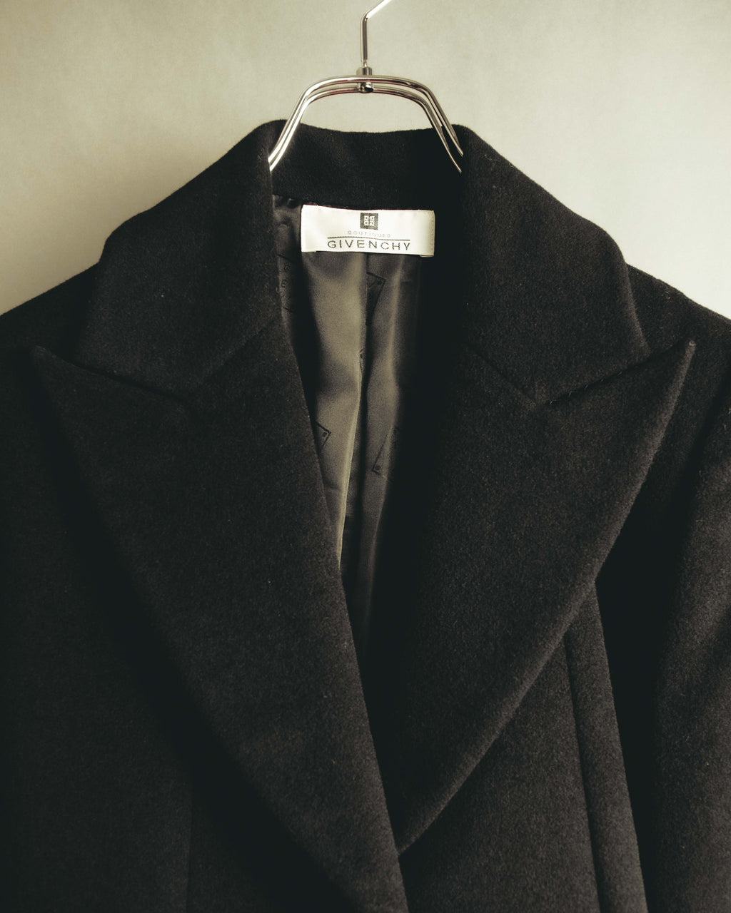 首元に残るBOUTIQUES GIVENCHYの織りタグと、大ぶりのノッチドラペルを捉えたディテールカット。起毛したブラック系ウール生地と総裏地の一部も確認できます。