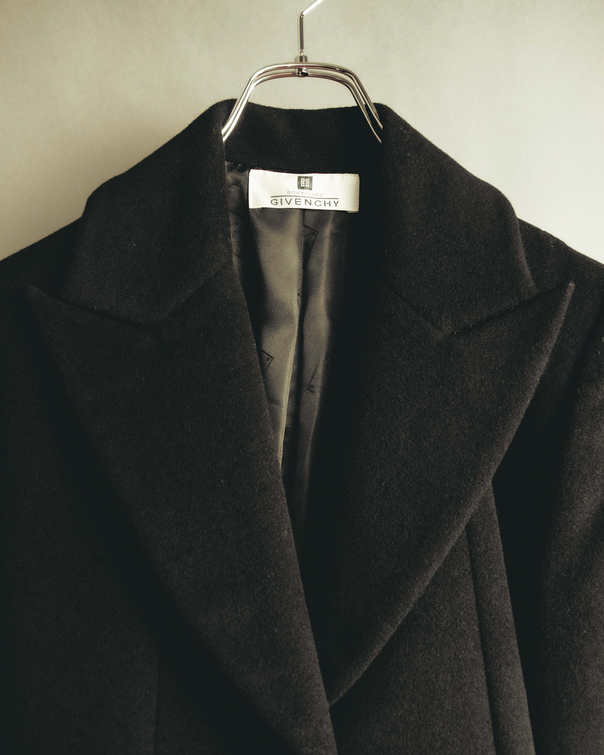 首元に残るBOUTIQUES GIVENCHYの織りタグと、大ぶりのノッチドラペルを捉えたディテールカット。起毛したブラック系ウール生地と総裏地の一部も確認できます。