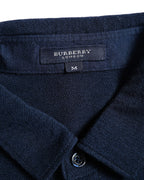 ネイビーのニット襟内側に配されたBURBERRY LONDONタグと、前立てのロゴ刻印入りシェルボタンを捉えたカット。
