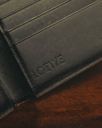 ブラックレザーの内装に配された、セリフ体の「LOEWE」ロゴ刻印を捉えたディテールカット。上部にはカードスロット、縁にはブラウン系のコバが確認できます。