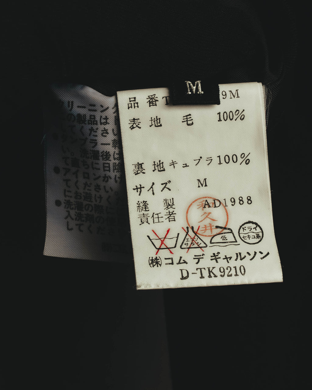 表地・毛100パーセント、裏地・キュプラ100パーセント、サイズMを記した内側の品質表示タグ。AD1988表記と日本製表記を確認できるカット。