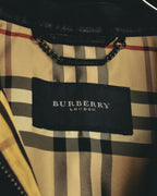 チェック柄の内側に配されたBURBERRY LONDONの織りタグと、襟裏のブランド刻印入り金属製吊りチェーンプレートを捉えたカット。ベージュを基調にブラック、ホワイト、レッド系のラインが走るチェック柄も確認できます。