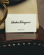 旧筆記体のSalvatore FerragamoロゴとMADE IN ITALY表記が確認できる付属カードを、ボーンカラーのシボ革とゴールドカラーのガンチーニ金具に添えたカット。