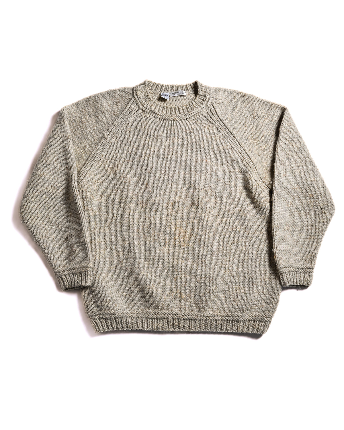 メランジ調ベージュのボディに、プレーンな天竺編みのフロントとラグランスリーブのラインを配した前面全体カット。しっかりと編み込まれたラウンドネックと裾・袖口のリブ仕様が確認できます。