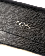 付属するシボ革仕様のブラックレザーケースに配された、CELINE PARISのロゴ刻印を捉えたディテールカット。細かなシボのあるレザー表面とフラップの縁が確認できます。