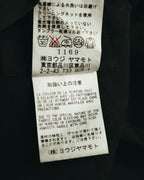 洗濯表示と取扱い上の注意を記した内側のケアタグ。水洗い・タンブラー乾燥に関する注意書きと、ヨウジヤマモトの表記が確認できるカット。