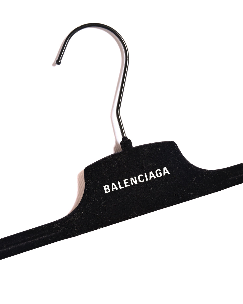BALENCIAGAロゴが白字で配されたブラックのハンガーを写した付属品カット。トラウザーズ本体のディテールや内タグではありません。