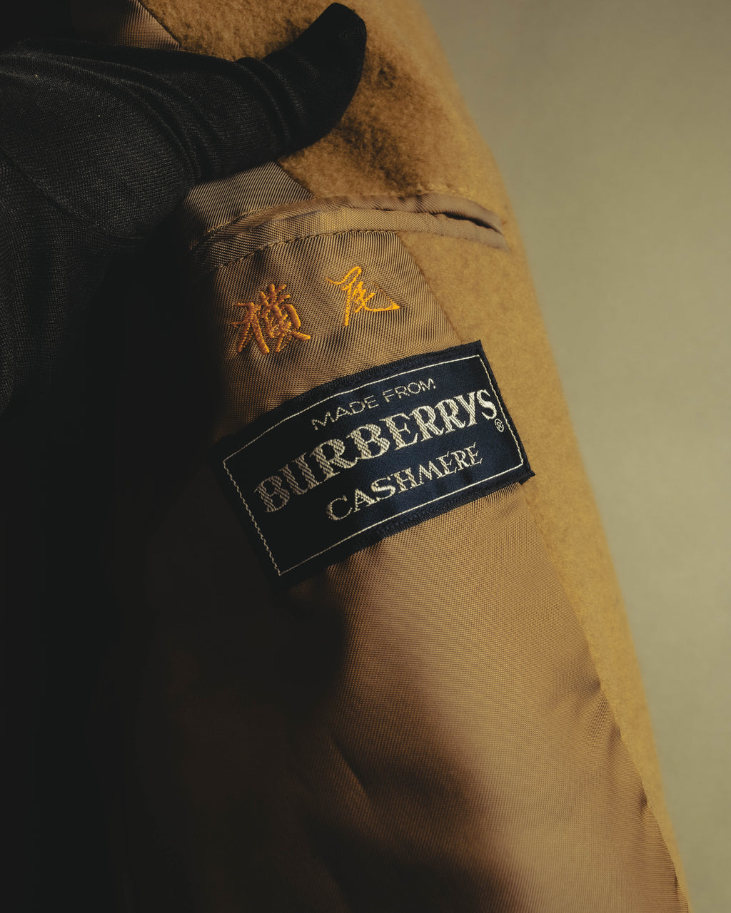 内側の「MADE FROM BURBERRYS CASHMERE」表記のブランドタグと、横尾と読めるネーム刺繍を捉えたカット。滑らかな裏地と表地の起毛感も確認できます。