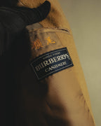 内側の「MADE FROM BURBERRYS CASHMERE」表記のブランドタグと、横尾と読めるネーム刺繍を捉えたカット。滑らかな裏地と表地の起毛感も確認できます。