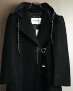白地に黒文字で「BALENCIAGA PARIS」と記された襟元のタグを捉えたカット。一体化したチャコールブラック調のフード、キルティング仕立ての裏地、異なる金属パーツを組み合わせたフロントの留め具も確認できます。