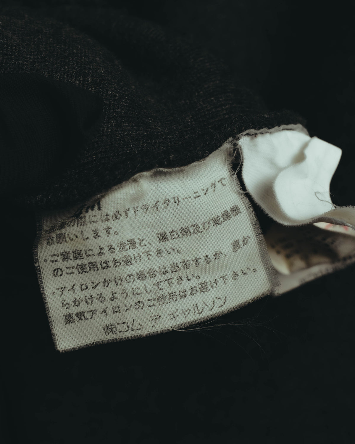 内側に配された品質表示タグのクローズアップ。株式会社コム デ ギャルソンの社名と、素材・洗濯表示が確認できるカットです。