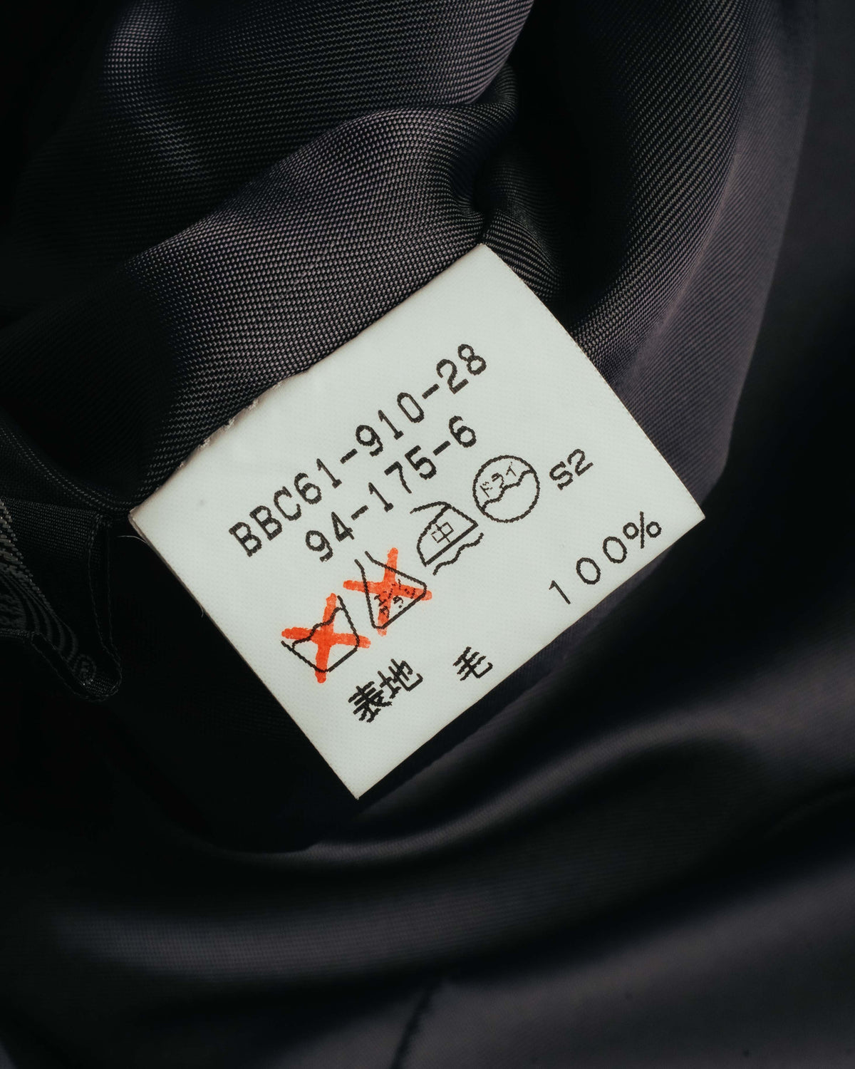 内側に残る旧形式の取扱絵表示タグのカット。品番表記「BBC61-910-28」と、表地の毛100%表記を確認できます。
