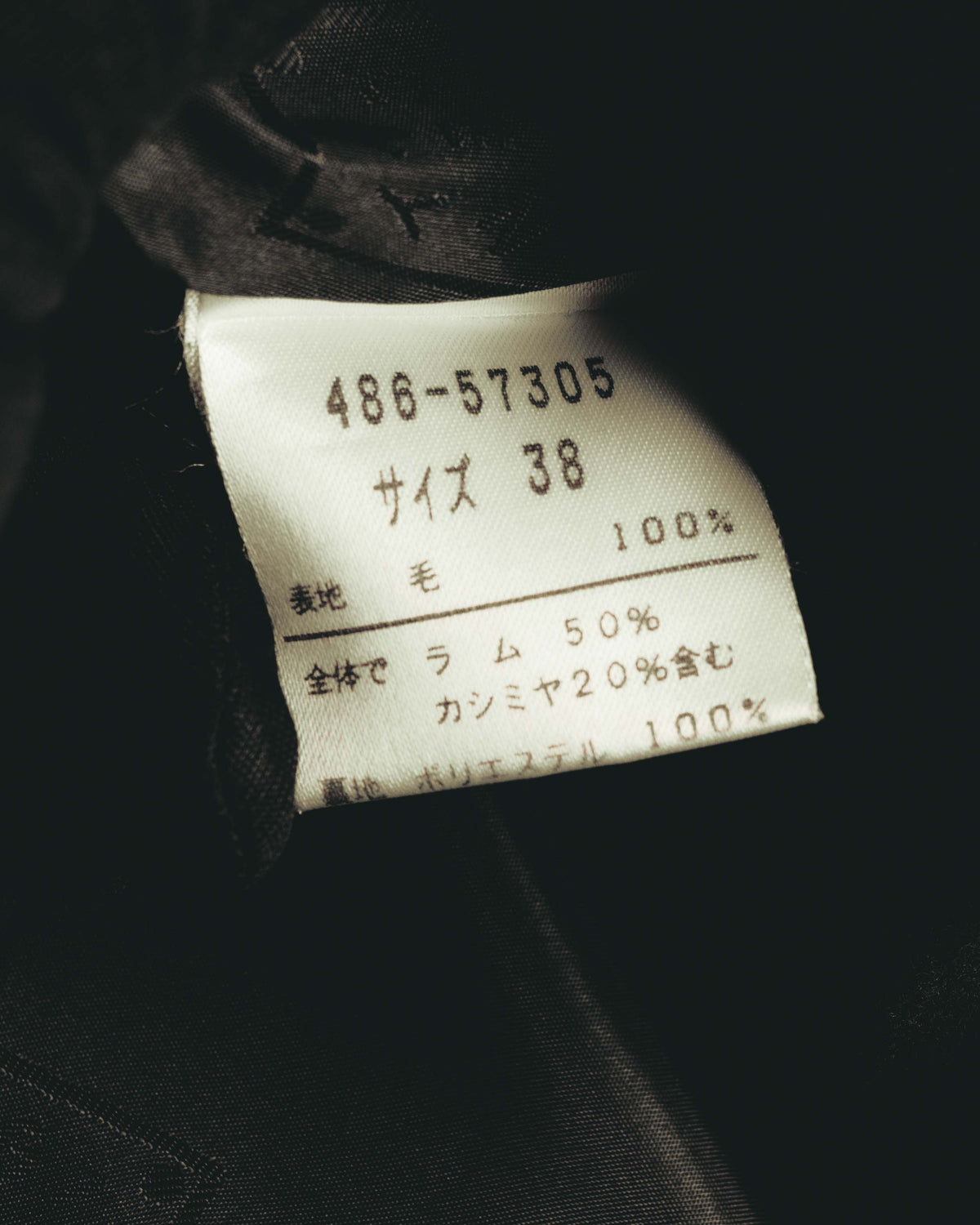 サイズ38と、表地がラム50%・カシミヤ20%を含む毛100%であることを確認できる品質表示タグのカット。